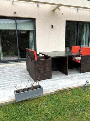 Un patio al aire libre con una mesa y sillas de comedor, una planta en maceta y un ventanal corredero.
