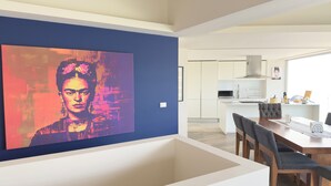 Cocina moderna con gabinetes blancos, un microondas y una estufa. Hay una zona de comedor con una mesa y sillas de madera.