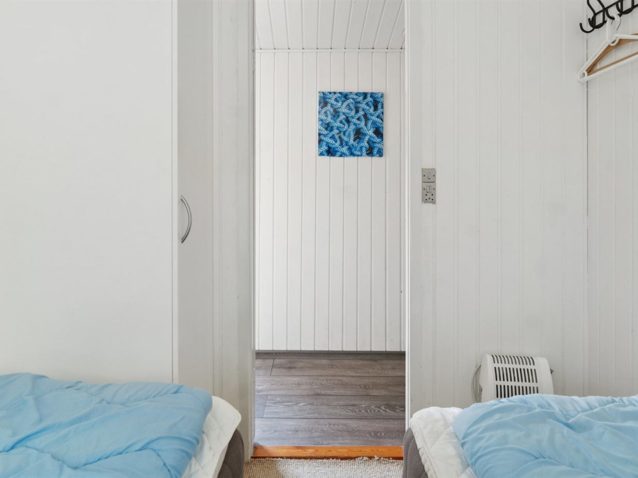 Una habitación con dos camas, un radiador y una ventana pequeña con cortina de estampado azul.