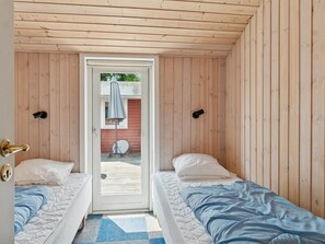 A room with two single beds, a door leading outside, and a view of a red building and a satellite dish. - "Rieke" -  from the sea by Interhome (Rørvig)