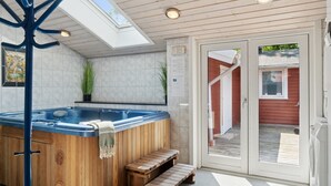 A spa area with a hot tub, wooden benches, a skylight, and a glass door leading outside. - "Rieke" -  from the sea by Interhome (Rørvig)