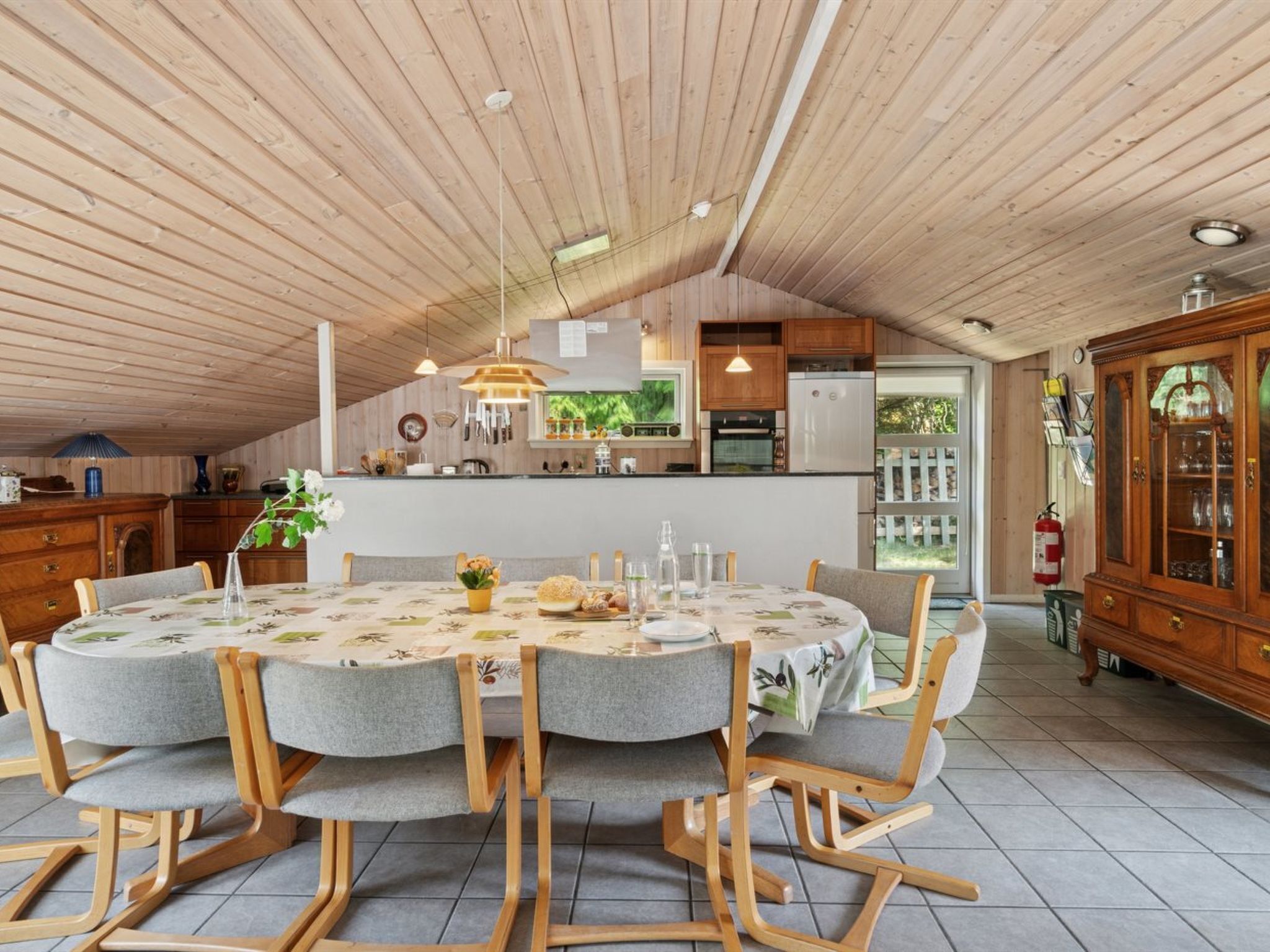 Un coin repas avec une table ronde, des chaises en bois et une cuisine en arrière-plan.
