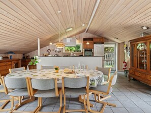 A dining area with a round table, wooden chairs, and a kitchen in the background. - "Rieke" -  from the sea by Interhome (Rørvig)
