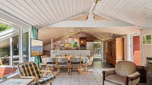A spacious living area with a dining table, chairs, and a fireplace. - "Rieke" -  from the sea by Interhome (Rørvig)