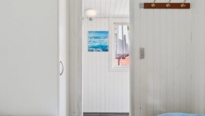 A room with two beds, a wooden floor, a painting of the ocean, and a window with a view of the outside. - "Rieke" -  from the sea by Interhome (Rørvig)