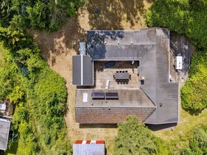 An aerial view of a house with a deck, solar panels, and a small outdoor seating area. - "Rieke" -  from the sea by Interhome (Rørvig)