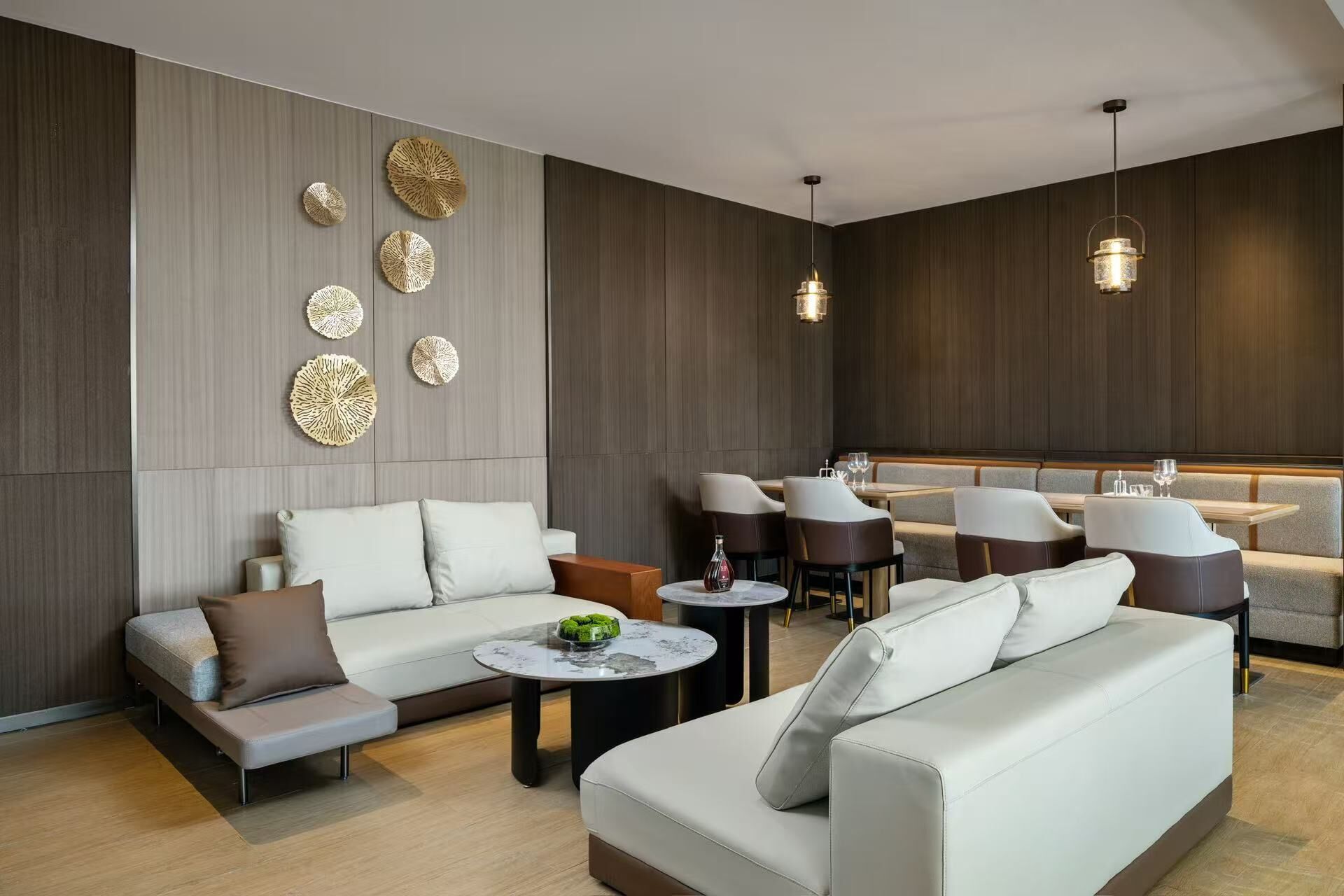 A modern living room with a sofa, armchairs, and a dining area with tables and chairs.