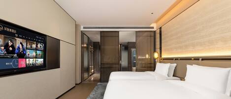Una habitación de hotel moderna con una cama grande, un televisor mostrando una película y un pasillo que conduce a un baño.
