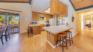 A spacious kitchen with wooden cabinets, a large island with stools, and a view of the outdoors.