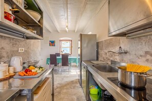 A modern kitchen with stainless steel appliances, a dining area with a table and chairs, and a view to the dining room.
