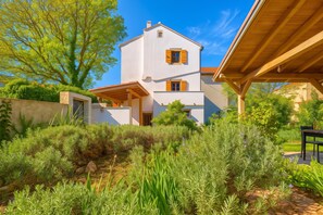 A two-story house with a white exterior and wooden shutters, surrounded by lush greenery and trees. - Casa Lussingrande Island Retreat With Terrace (Mali Losinj)