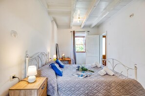 Un dormitorio con cama, mesita de noche, lámpara y ventana con cortinas.
