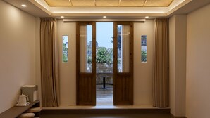 A modern interior with a wooden door leading to an outdoor area, a small table, and a kettle on a shelf. - Zen Den Design (Shantou)