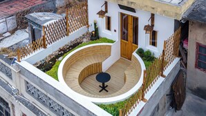 A circular wooden deck with a table in the center, surrounded by a white wall and a wooden fence. - Zen Den Design (Shantou)