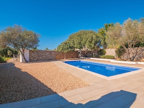 A swimming pool with a stone wall and trees in the background.