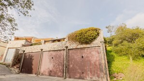Een stenen muur met een houten poort, een trap en een gebouw met een balkon.