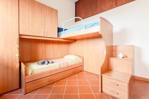 Una habitación pequeña con una cama litera, un escritorio y un armario.