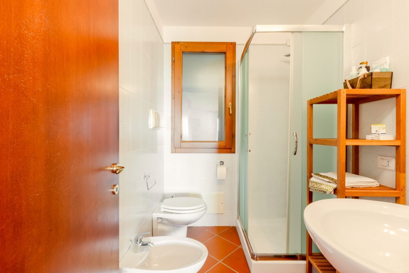 A bathroom with a toilet, bidet, sink, and glass shower enclosure.