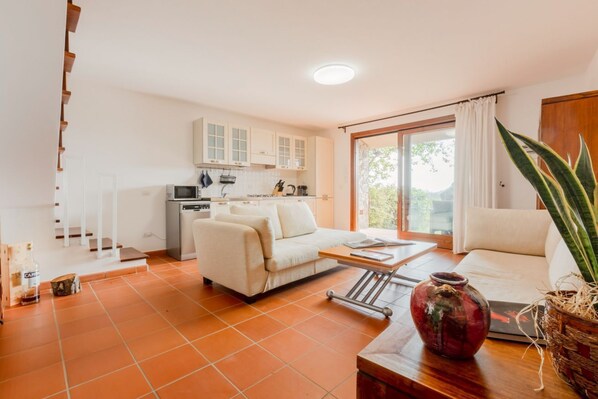 Un espacio habitable compacto con kitchenette, un sofá, una mesa de centro y un ventanal grande.