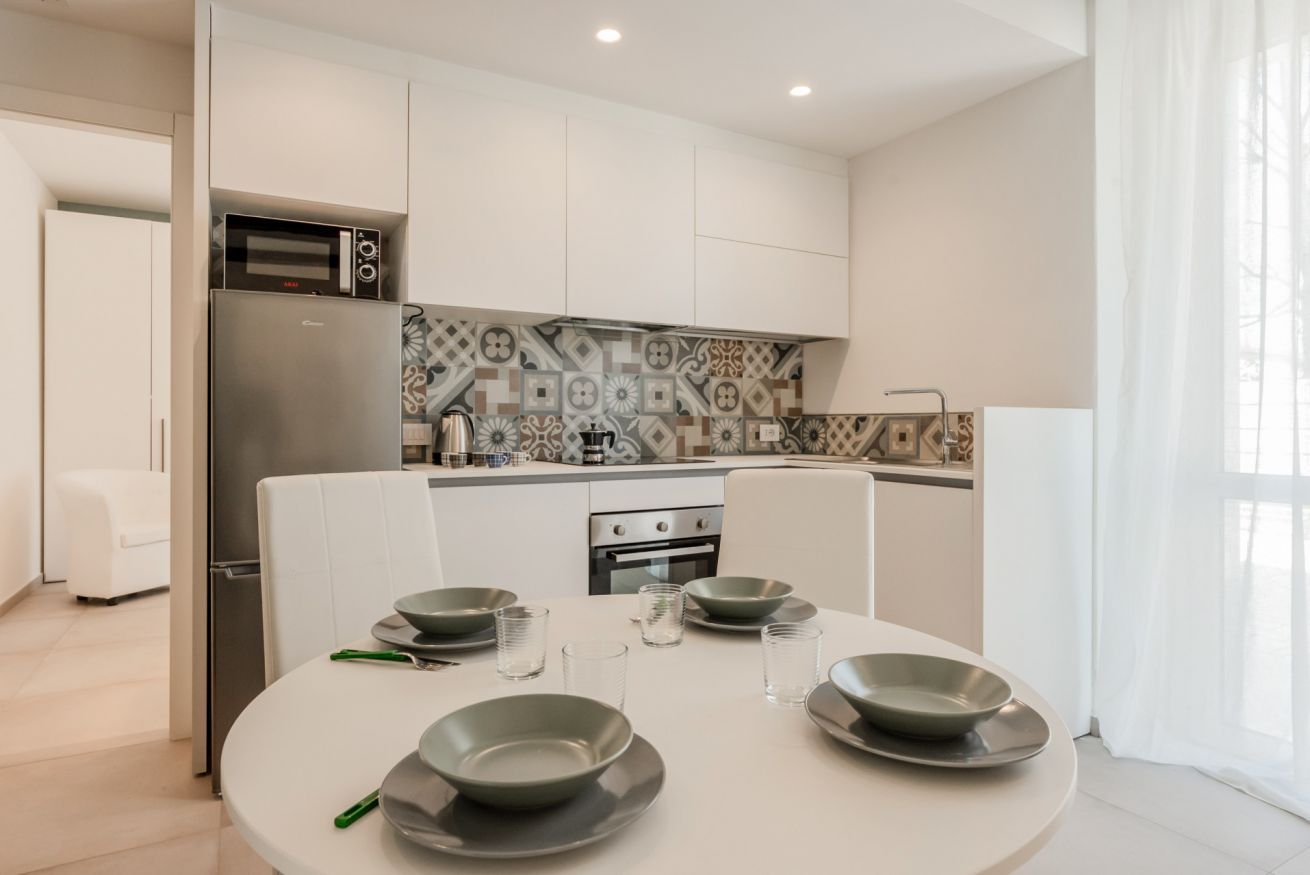 Een moderne keuken met witte kasten, een ingebouwde oven en een decoratieve achterwand.