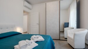 Ein modernes Hotelzimmer mit einem Bett, einem Sessel, einem Spiegel und einer Tür.