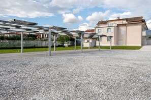 A building with a modern design, a covered outdoor area with a gravel floor, and a fence in the background.
