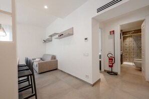 A modern interior with a dining area, sofa, and a fire extinguisher. - GuestHost - Mare Monti Apartment 4 (Dogana)