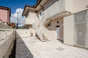 A residential building with a staircase leading to an upper floor, a gated entrance, and a view of the surrounding area. - GuestHost - Mare Monti Apartment 4 (Dogana)