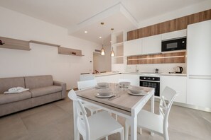 A modern kitchen with white cabinets, a microwave, and a dining area with a table set for four.