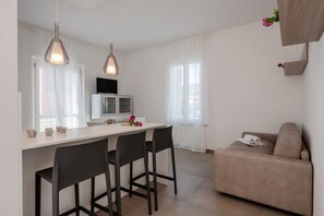 A modern kitchen with a dining area, a sofa, and a TV. - GuestHost - Mare Monti Apartment 4 (Dogana)