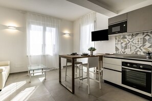 Une cuisine moderne équipée d’une table à manger, de chaises, d’un téléviseur et d’un four à micro-ondes.