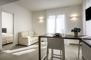 Une pièce moderne et bien éclairée, comprenant une table à manger, un canapé et un téléviseur fixé au mur.