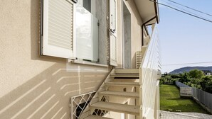 A set of outdoor stairs leading to a building with a beige exterior and white shutters.