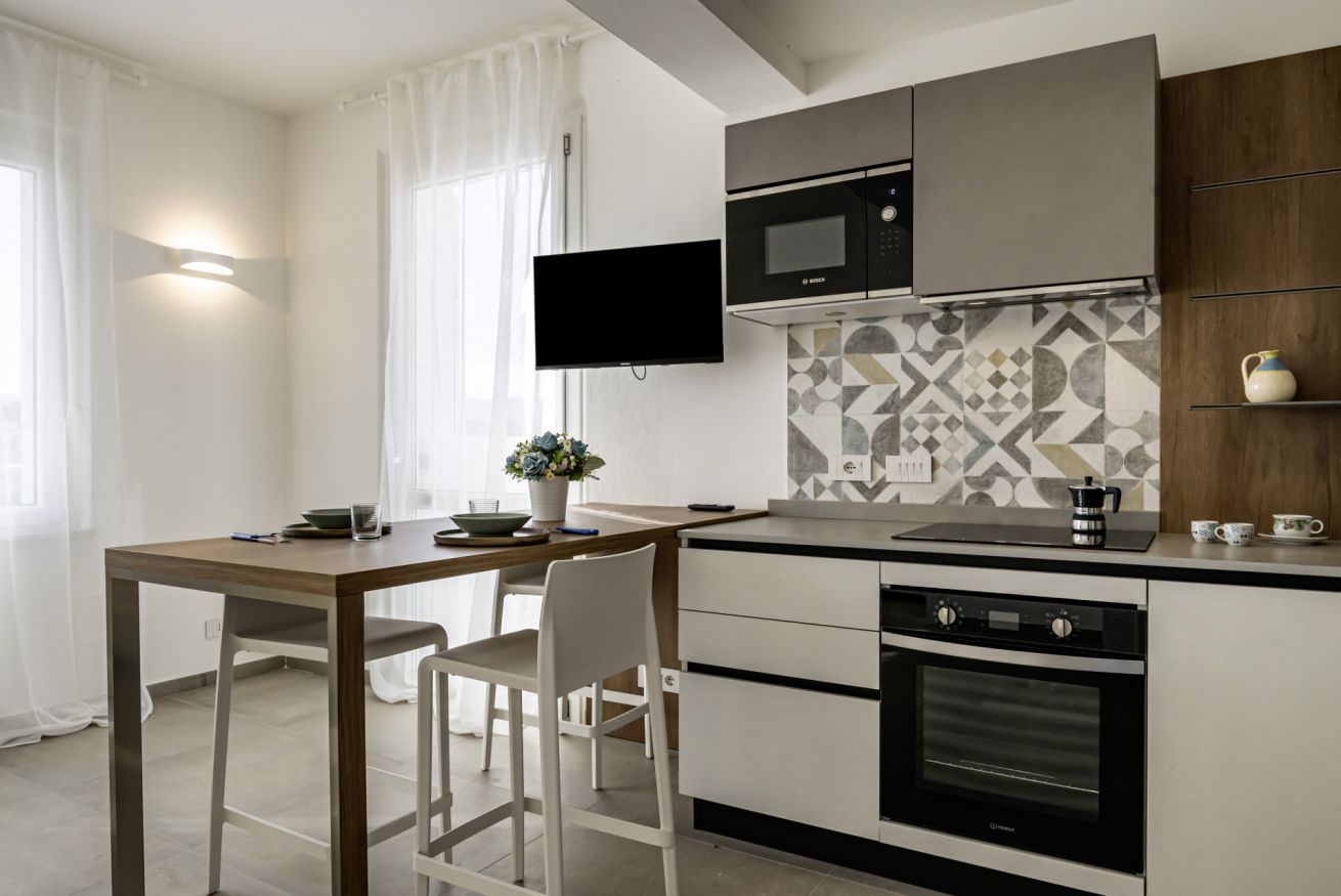 A modern kitchen with a flat-screen TV, a microwave, an oven, and a coffee maker.