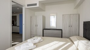 A bedroom with a bed, a dresser, a mirror, and a wardrobe.