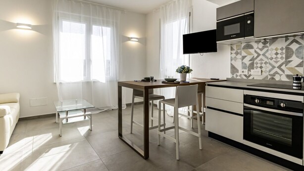 A modern kitchen with a dining table, chairs, a TV, and a microwave.