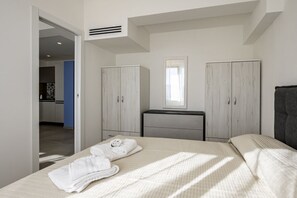 A bedroom with a bed, a dresser, a mirror, and a wardrobe. - GuestHost - Mare Monti Apartment 5 (Dogana)