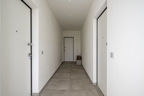 A hallway with white walls, a tiled floor, and two doors on either side. - GuestHost - Mare Monti Apartment 5 (Dogana)