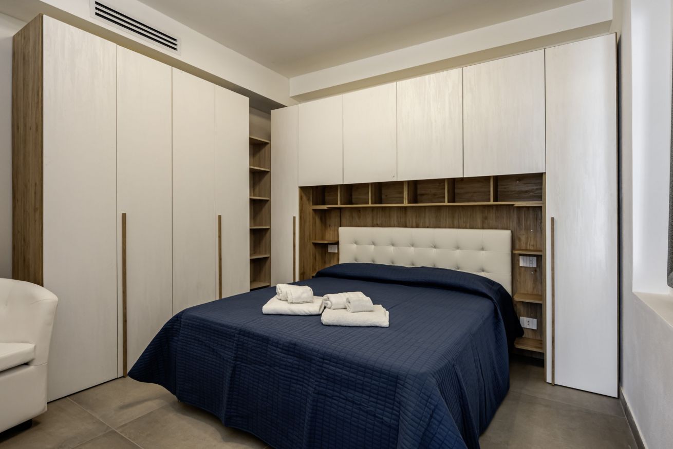 Een slaapkamer met een bed, een dressoir en een kledingkast.