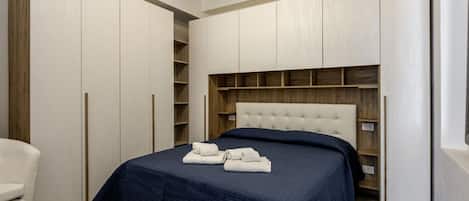 A bedroom with a bed, a chest of drawers, and a wardrobe.