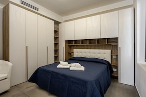 A bedroom with a bed, a chest of drawers, and a wardrobe. - GuestHost - Mare Monti Apartment 6 (Dogana)