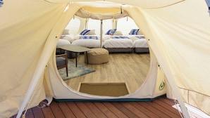 Teltta, jossa on useita sänkyjä, pieni pöytä ja penkki.