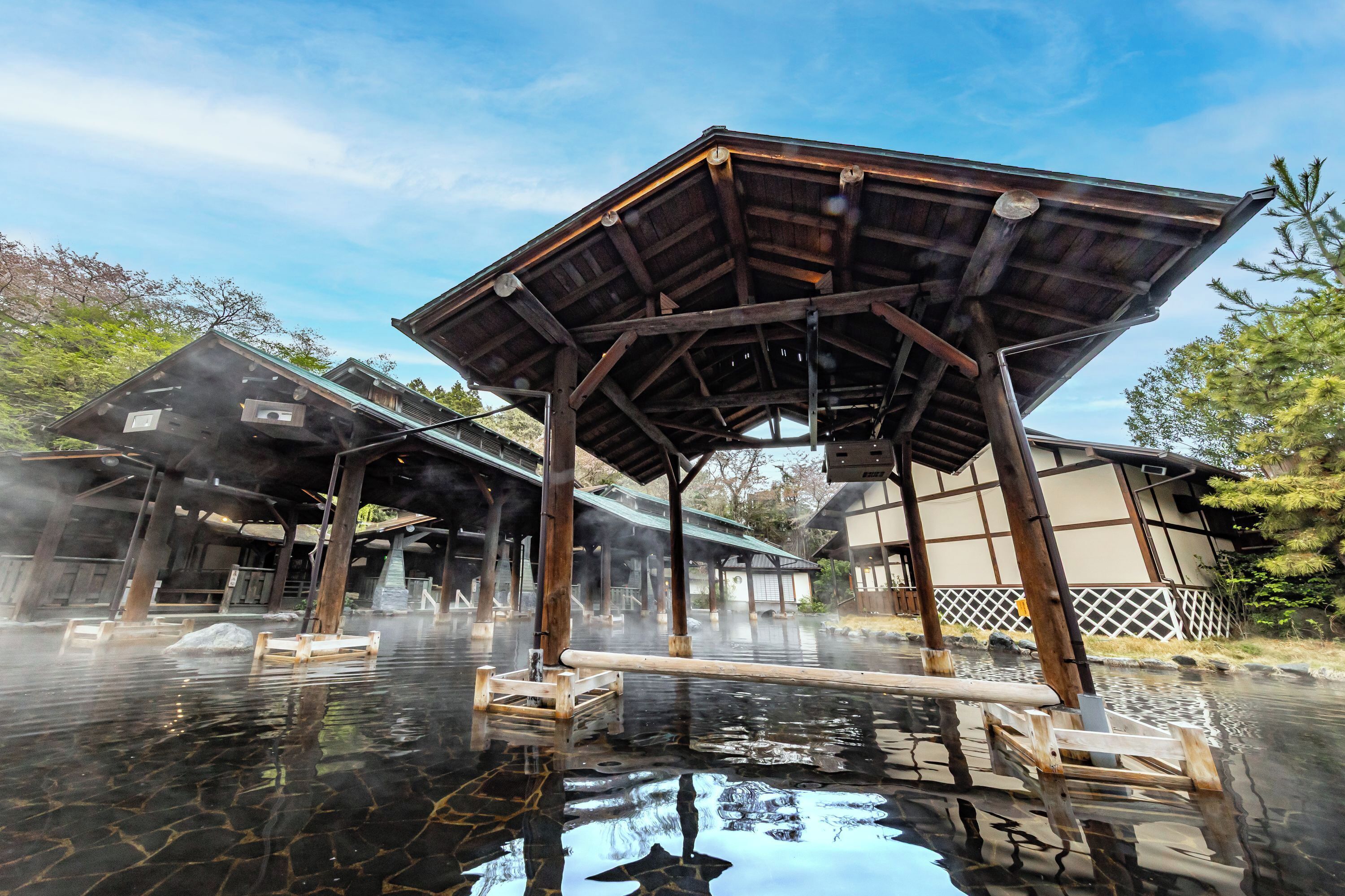 Un onsen japonais traditionnel, avec des structures en bois et des bains d’eau chaude.