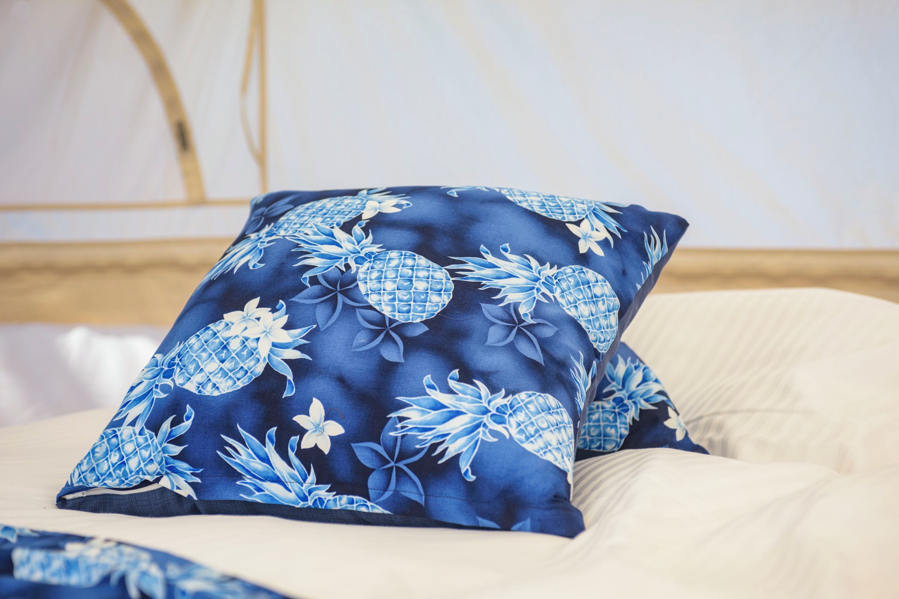 A bed with a blue floral pillow and a white pillow.