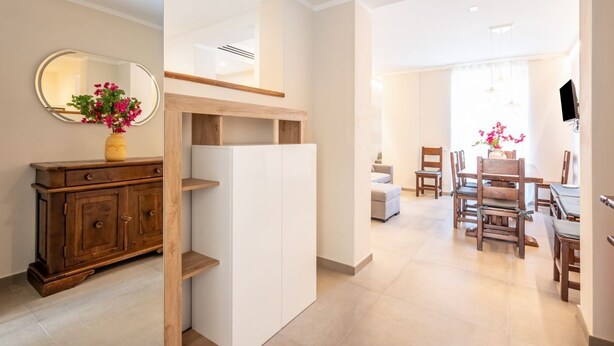 Un intérieur moderne avec un meuble en bois, une étagère blanche et un coin repas comprenant des chaises et une table en bois.