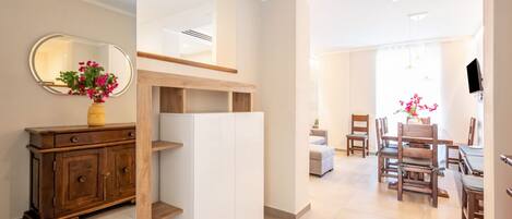 A modern interior with a wooden cabinet, a white shelving unit, and a dining area with wooden chairs and a table.