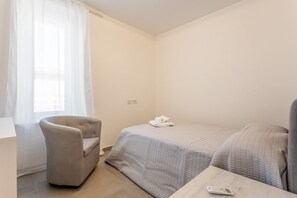 Een kleine, schone kamer met een bed, een stoel en een tafel.