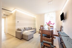 Een moderne woonkamer met een bank, eettafel en stoelen.