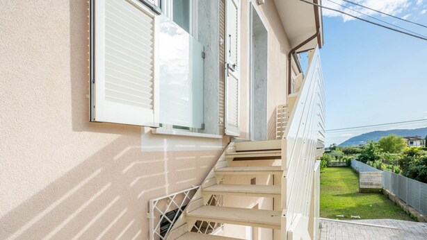 Een trap die leidt naar een balkon met uitzicht op een tuin en heuvels.