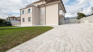 Una moderna casa a due piani con vialetto lastricato e piccolo prato.